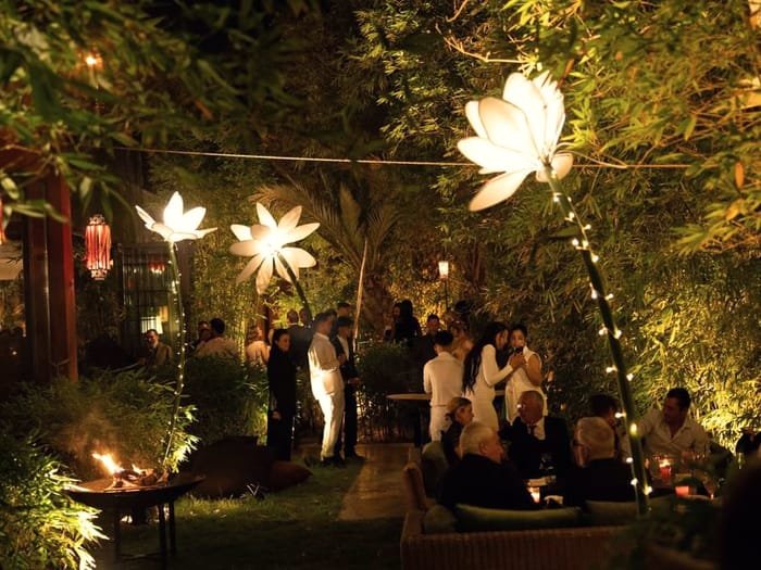 An evening garden reception lit by lanterns and illuminated flower sculptures.